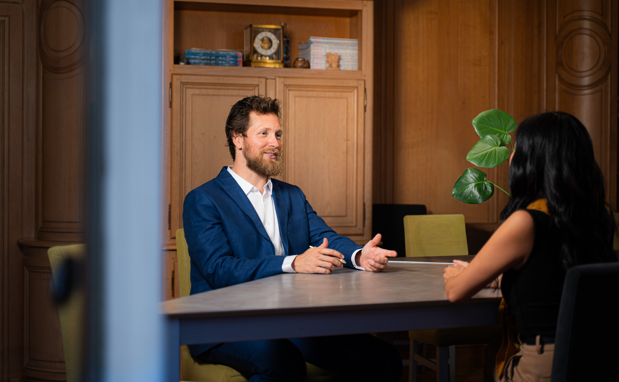 Zach Evans in conversation with a client across a table in a wood-paneled study
